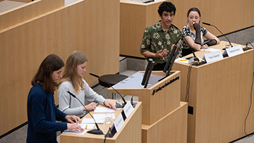Vier Jugendliche an Rednerpulten im Plenarsaal
