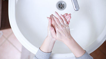 Aufsicht auf Hände beim Waschen über einem Waschbecken