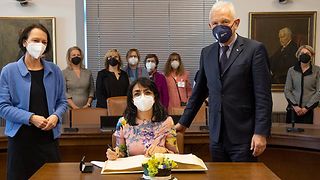 Muhterem Aras sitzt vor dem Goldenen Buch, neben ihr Oberbürgermeister Harry Mergel und Susanne Bay