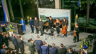 Die Musiker stehen zusammen mit Landtagspräsidentin Aras und Generalmusikdirektor Meister auf der Bühne