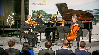 Kathrin Scheytt spielt Violine, Zoltan Paulich spielt Violoncello, dahinter Andrej Jussow am Flügel