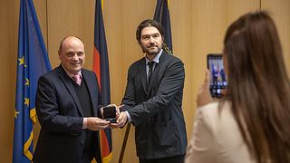 Landtagsvizepräsident Daniel Born überreicht dem griechischen Generalkonsul Symeon Linardakis einen Bildband und eine Silbermünze als Geschenk