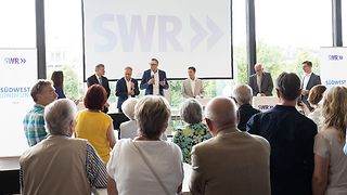 Die Fraktionsvorsitzenden auf der Bühne in der Lobby vor Besuchern