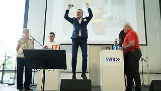 Andreas Stoch (SPD) auf der Bühne beim Spiel Berufe raten