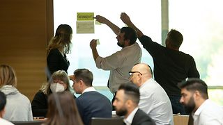 Teilnehmende kleben Zettel mit Ideen an eine Glasscheibe