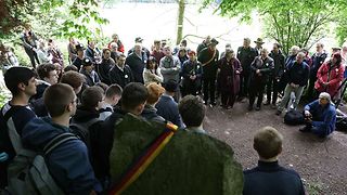 Die Wandergruppe steht im Kreis am Gedenkstein.