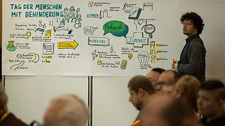Junger Mann an einem Plakat, auf dem wichtige Diskussionspunkte für den Tag stehen