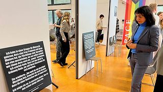 Landtagspräsidentin Aras betrachtet ein Ausstellungsschild.