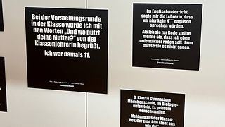 Schwarze Ausstellungsschilder mit weißer Schrift erzählen von rassistischen Erfahrungen.