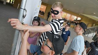 Der gefasste Dieb wird im Landtag von Kindern mit Handschellen gefesselt.