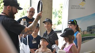 Kinder schauen auf eine Frisbee, die als Geschenk verteilt wird.