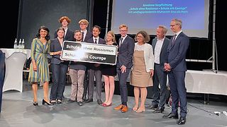Gruppenbild mit Muhterem Aras, Schülerinnen und Schülern und einem Schild mit Aufdruck "Schule ohne Rassismus, Schule mit Courage"