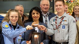 Muhterem Aras, eine Pfadfinderin und ein Pfadfinder halten das Friedenslicht.