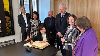 Gruppenbild: Rita Süssmuth trägt sich ins goldene Buch ein.