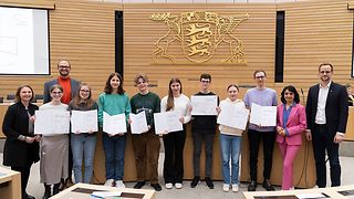 Die Siegerinnen und Sieger zeigen ihre Urkunden im Plenarsaal