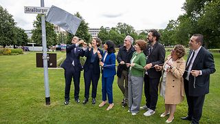Viele Menschen stehen in einer Reihe und ziehen Bedeckung des Schildes weg 