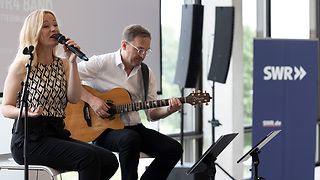 Eine Sängerin und ein Gitarrist auf der Bühne in der Lobby