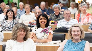 Landtagspräsidentin Aras verfolgt zusammen mit Besuchern einen Beitrag im Plenarsaal