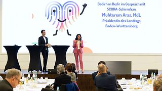 Aras spricht ins Mikrofon auf der Bühne