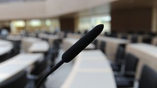 Ein Mikrofon in einer Bankreihe im Plenarsaal