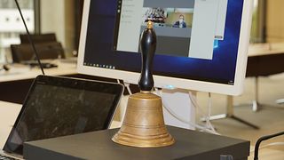 Eine Glocke steht vor einem Bildschirm