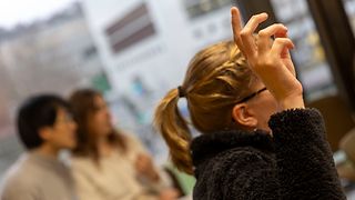 Eine Person meldet sich mit erhobenem Finger 