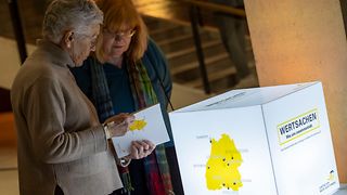 Zwei Frauen stehen vor einem Wertsachen-Lampenschirm