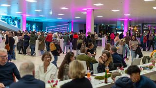 Gäste sitzen und stehen an Tischen in der Lobby