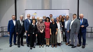 Gruppenfoto mit Teilnehmenden und Gästen auf der Bühne