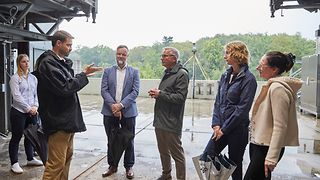 Ein Mitarbeiter des DLR erzählt den Besucherinnen und Besuchern etwas zum Prüfstand, in dem sie stehen.