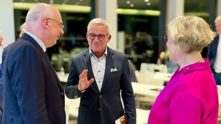 Landtagspräsident Strobl tauscht sich mit zwei Personen aus, die ihm gegenüber stehen
