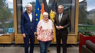 Landtagspräsident Strobl posiert vor den Fahnen der EU, Deutschlands und Baden-Württembergs mit der stellv. Landesobfrau und dem Landesobmann der Sudetendeutschen Landsmannschaft.